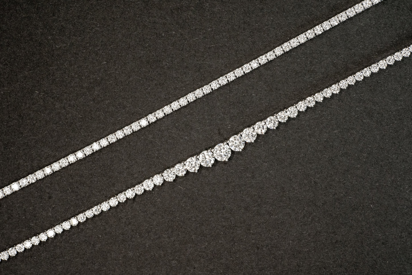 8.4 carat lab-grown tennis necklace in white gold next to 12 carat lab-grown white gold graduated diamond infinity tennis necklace